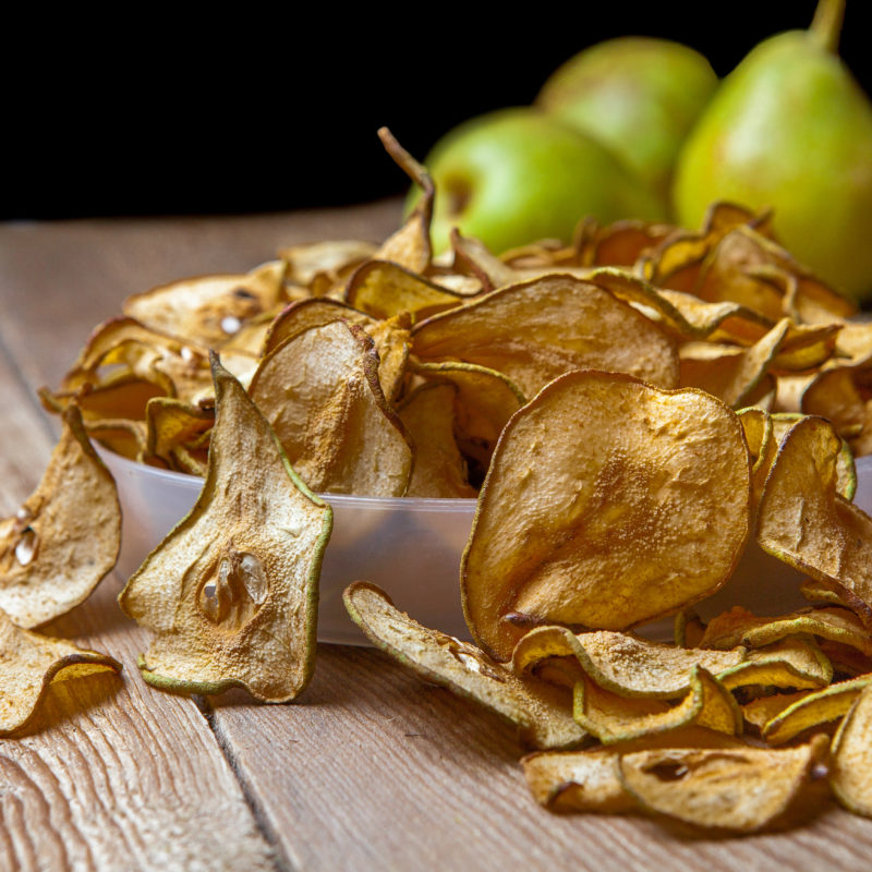 Close-up dried pears in plate and fresh pears on wooden table